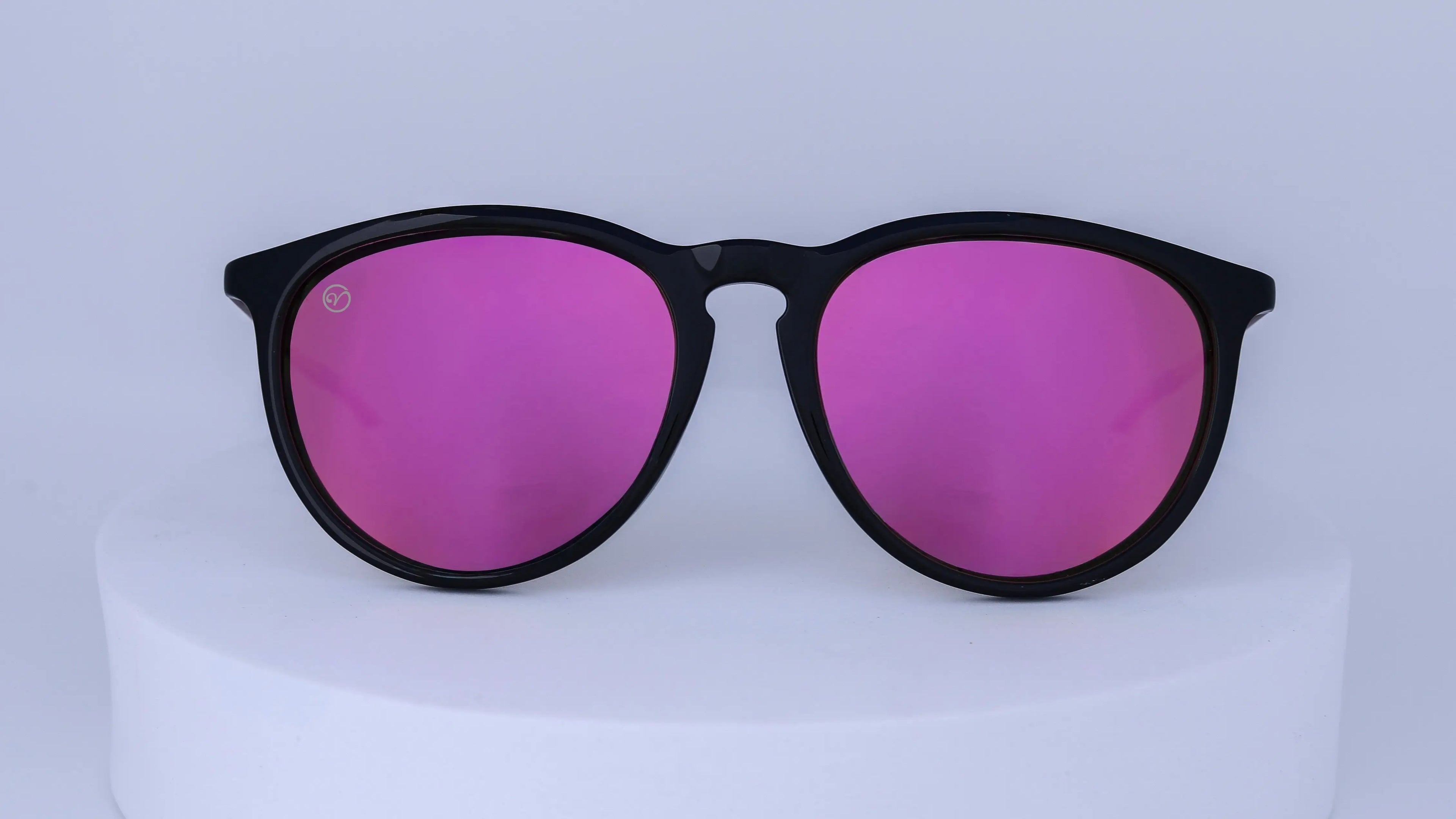 Sunglasses with black frames and pink lenses on a white background