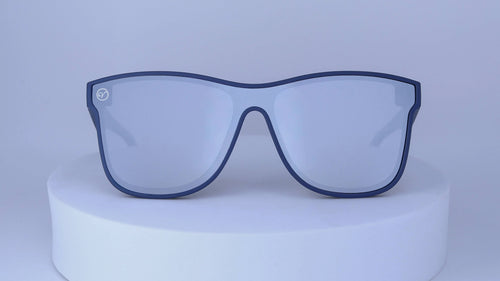 Blue sunglasses on a white pedestal against a white background