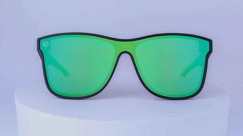Green sunglasses on a white pedestal with a white background