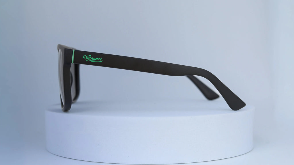 Black sunglasses with green Vybrance logo on a white background