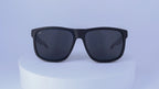 Black sunglasses on a white pedestal against a white background