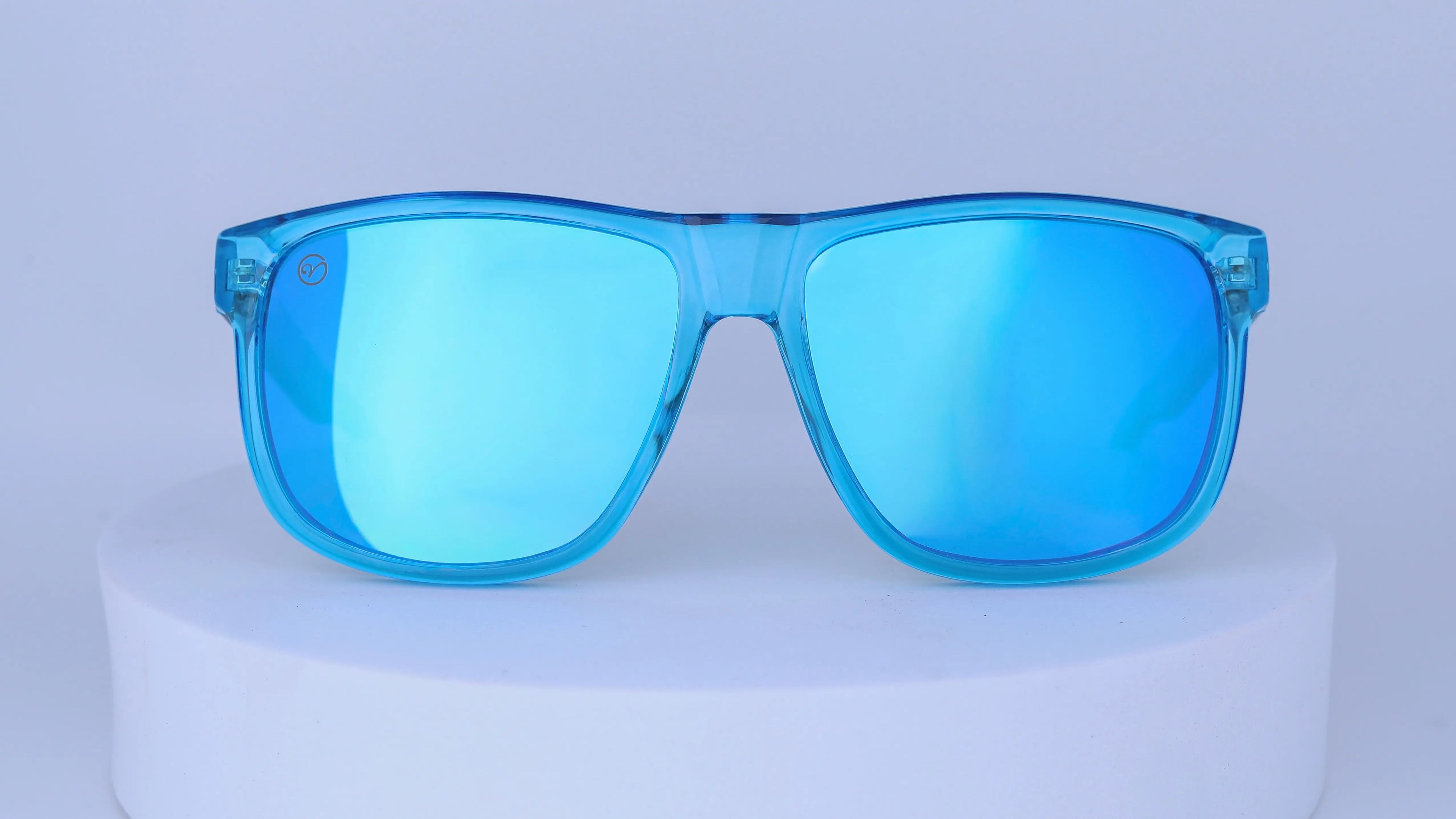 Blue sunglasses on a white pedestal against a white background